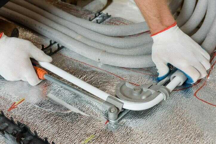 Pracownik montujący rury do ogrzewania podłogowego